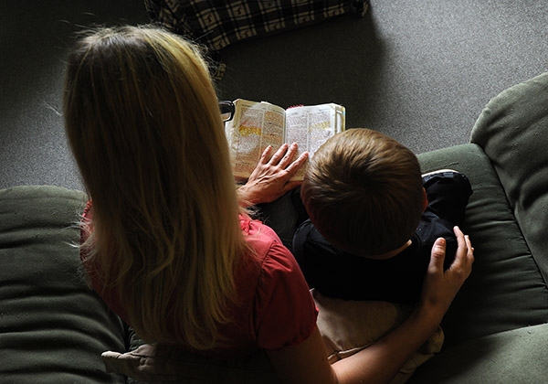 A pregnant young mother, who is a survivor of domestic violence, prays the Bible with her son. (Dan Cappellazzo/Staff Photographer)